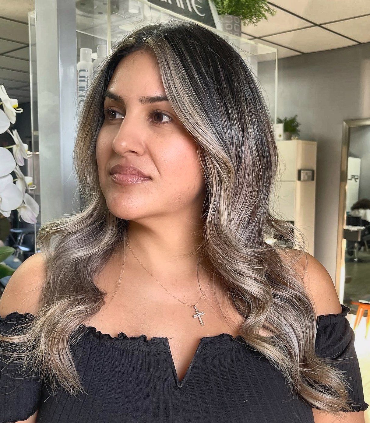 A Salon 1971 client with her finished ash-blonde balayage, orchids and the mirrors behind her